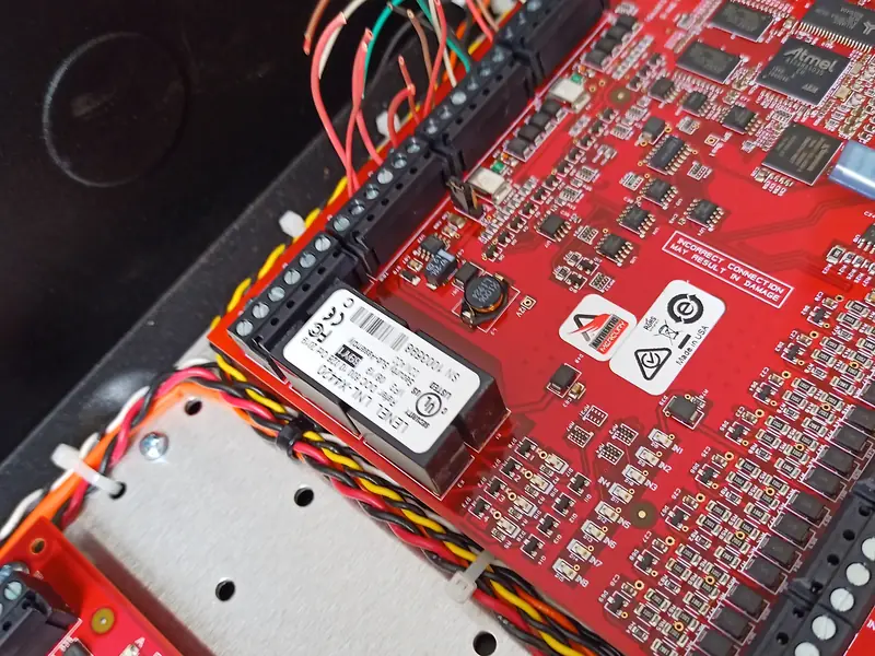 Close view of a Mercury MR52 sub-controller board with twisted-pair reader and door contact cables dressed along its edge in Mississauga, ON.