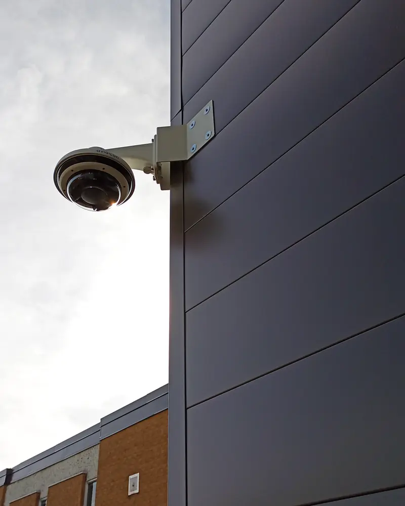 Avigilon multi-sensor panoramic security camera on a heavy-duty wall arm against corrugated dark metal cladding at a 150,000 sq ft warehouse in Vaughan, ON.