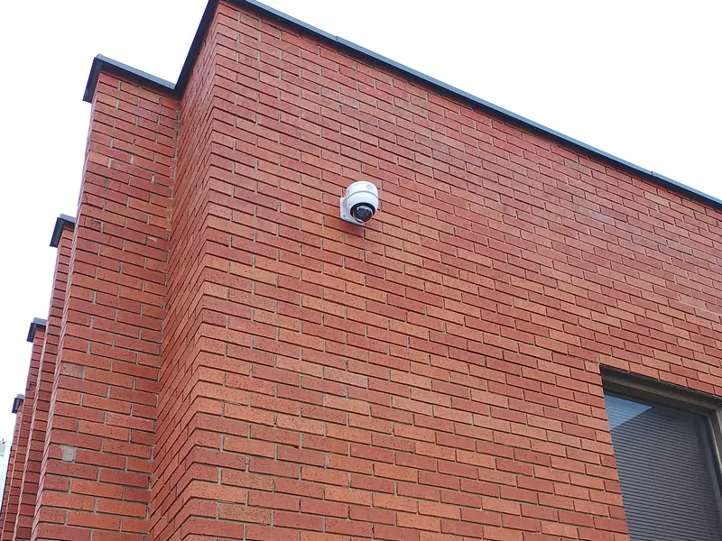 Two Axis & Avigilon outdoor vandal-resistant dome cameras mounted on a commercial brick facade covering the parking lot and entry in Mississauga, ON.