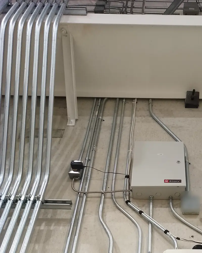 Bank of parallel EMT conduits with matched offsets running down a concrete telecom room wall into Mercury and ICT enclosures in Vaughan, ON.