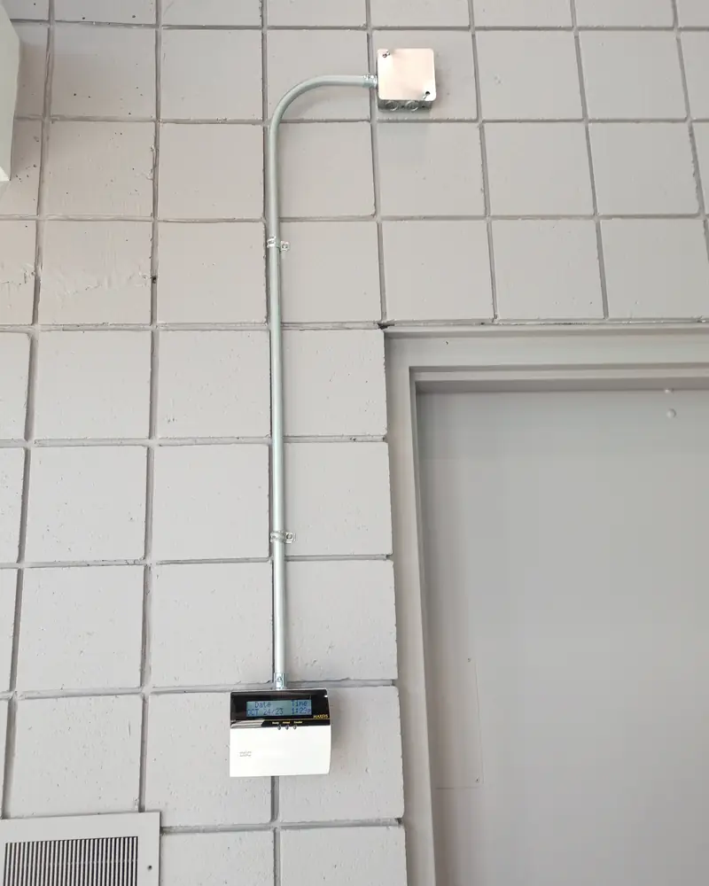 Surface EMT conduit drop running down a painted block wall from a pull box to a DSC Maxsys commercial keypad in Toronto, ON.