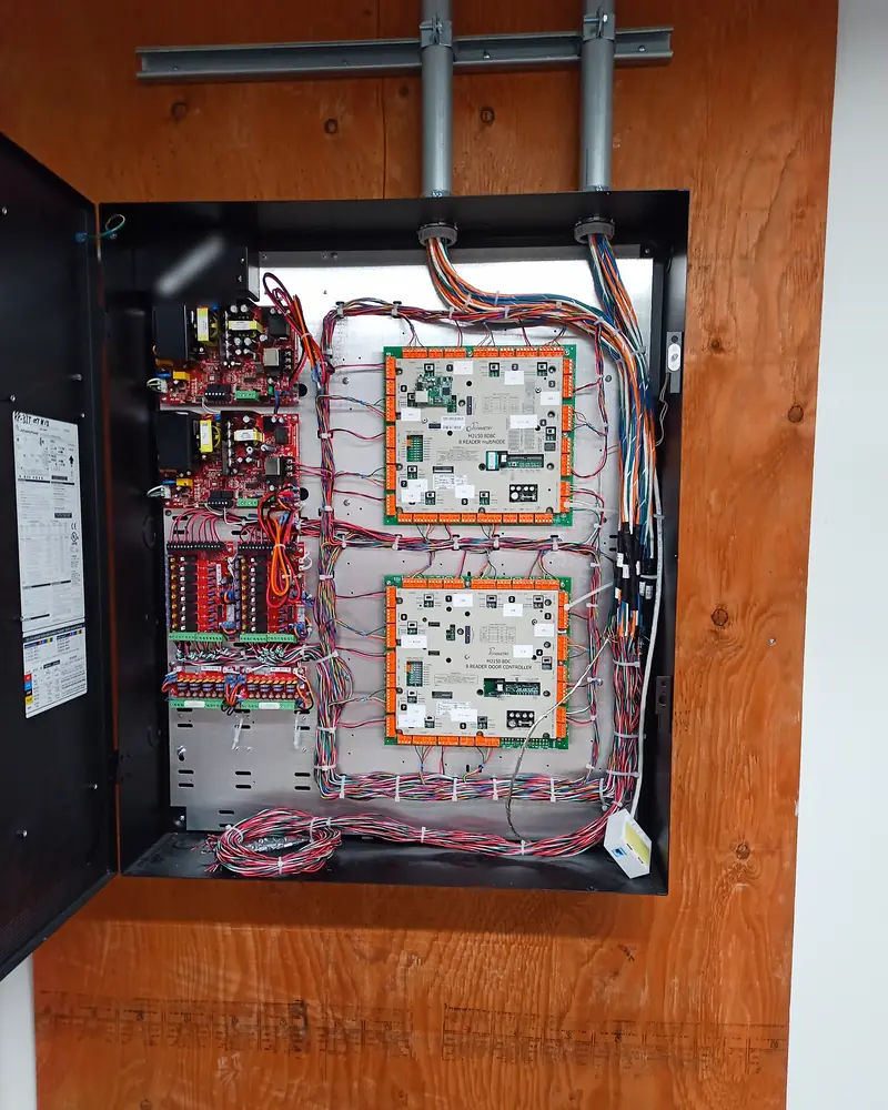 Dual Mercury access control panels and power distribution enclosure on a telecom backboard fed by EMT conduit at a 150,000 sq ft logistics warehouse in Vaughan, ON.