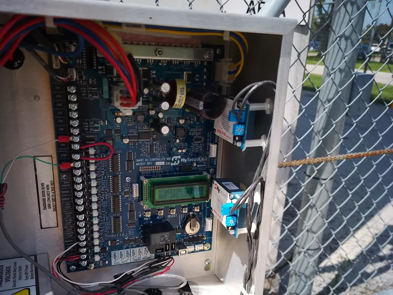 Open control cabinet of a commercial sliding gate operator wired with loop detector relays and access control dry contacts in Caledon, ON.