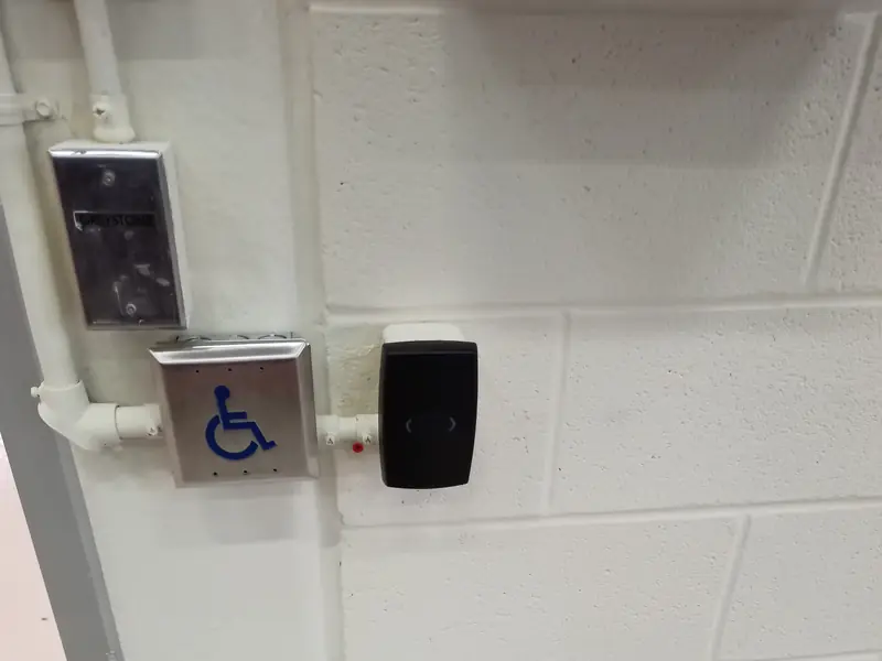 HID smart-card reader installed beside a barrier-free accessible door operator push button at a commercial facility in Oakville, ON.